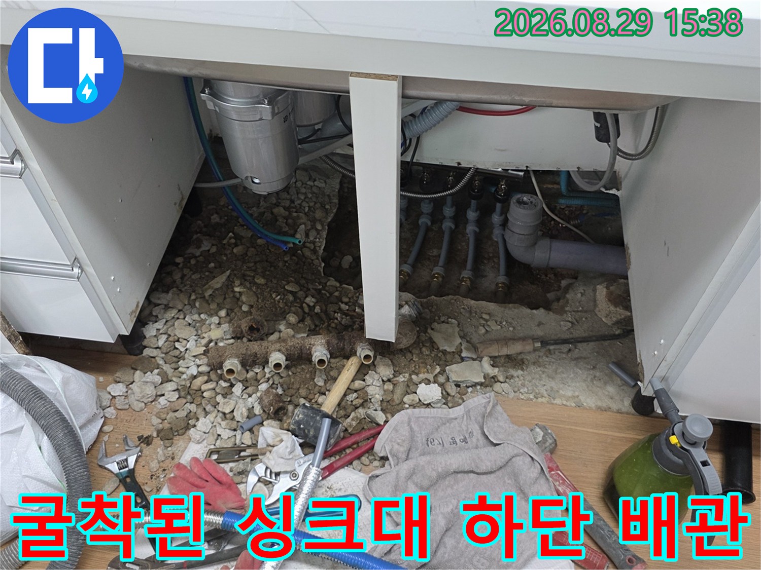 싱크대 아래 흙을 파헤쳐 노출시킨 매립 배관과 작업 도구