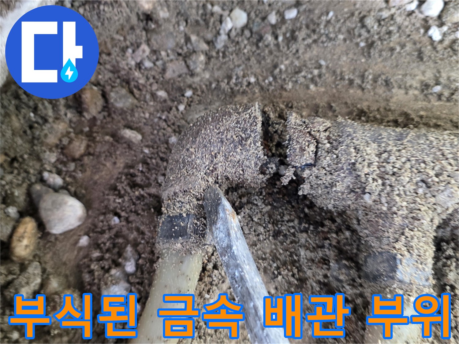 자갈과 흙에 덮여 있는 부식된 분배기 연결부