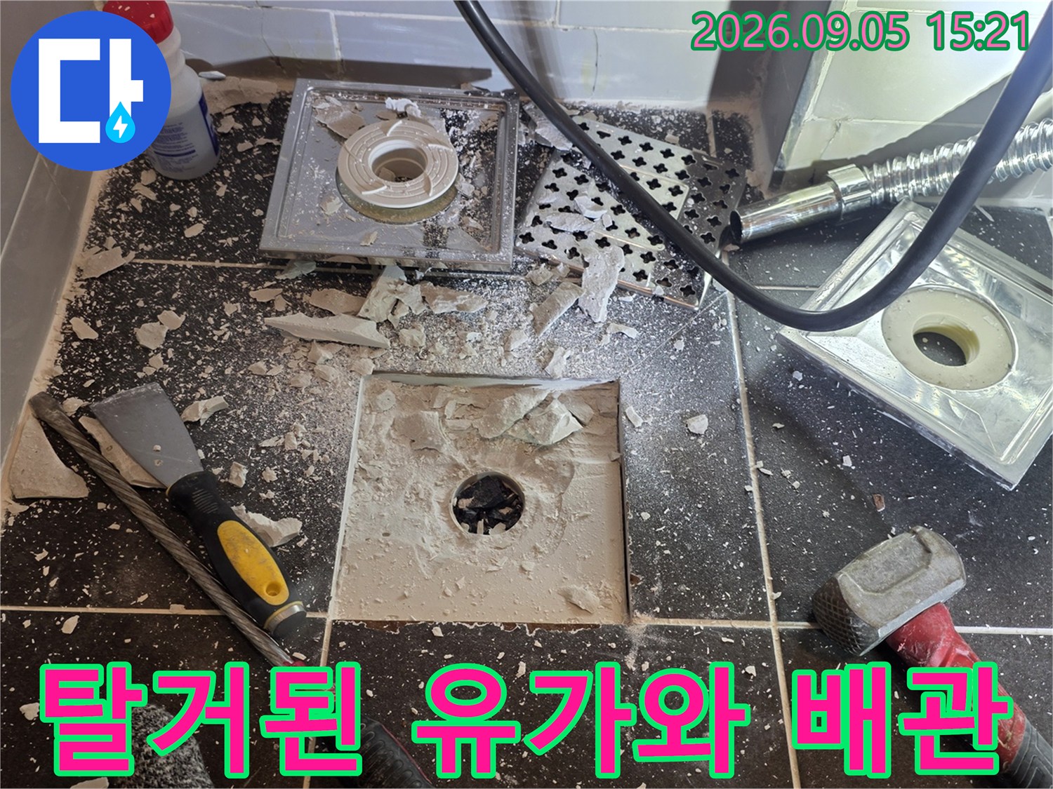 욕실 바닥 타일을 제거하여-배수관 연결 부위를 노출시킨 작업 장면