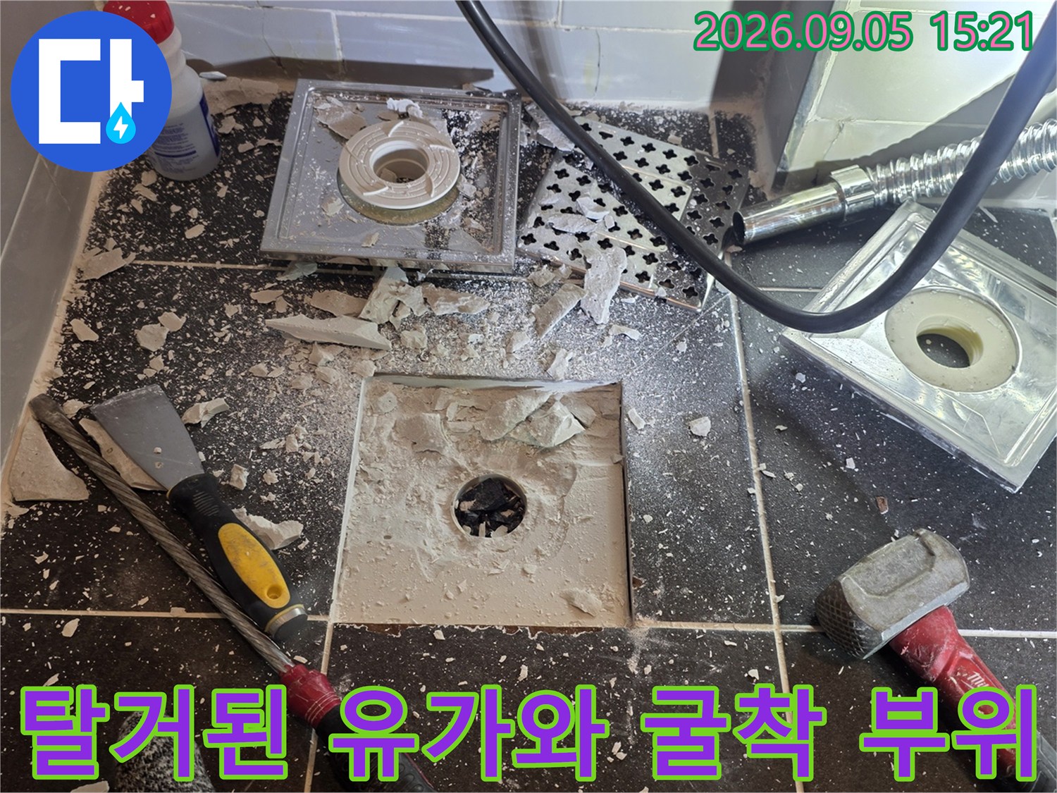 욕실 배수구 주변의 타일을 제거하고 배관을 노출시킨 상태