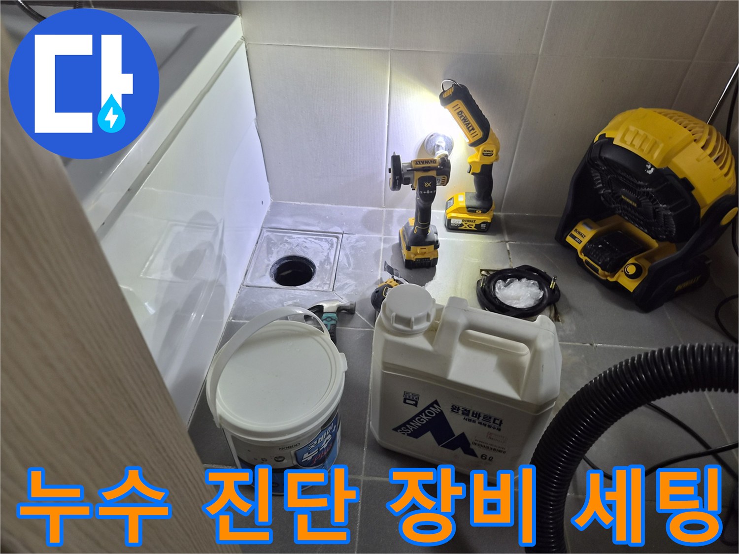화장실 바닥에 배치된 전동 공구와 청소용 흡입기 장비