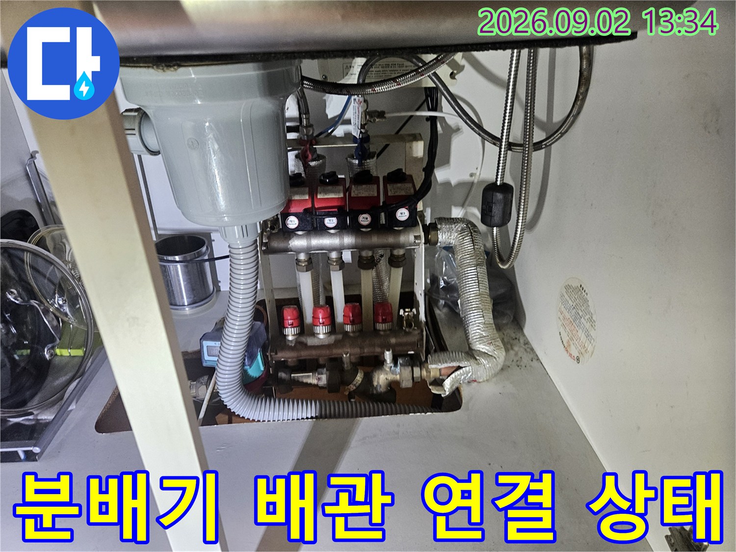 은색 보온재로 감싸진 배관과 붉은색 밸브가 있는 분배기 모습입니다.
