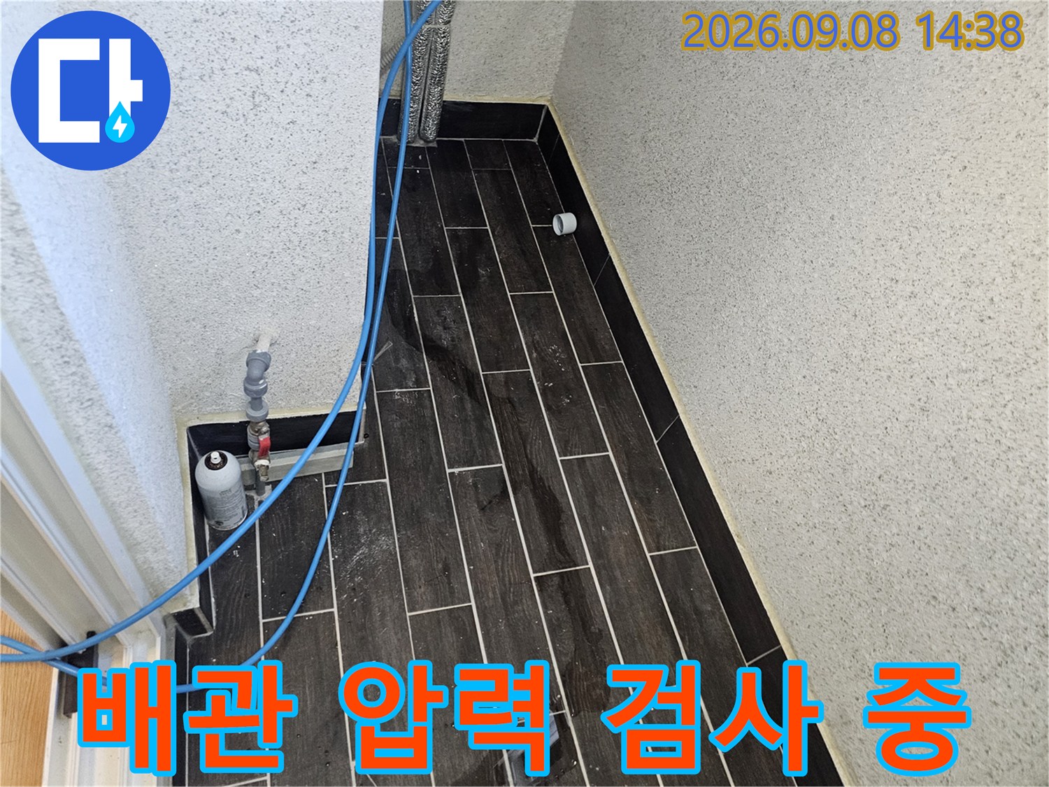 어두운 타일 벽면-파란색 호스가 연결된 배관의 공압 테스트 과정