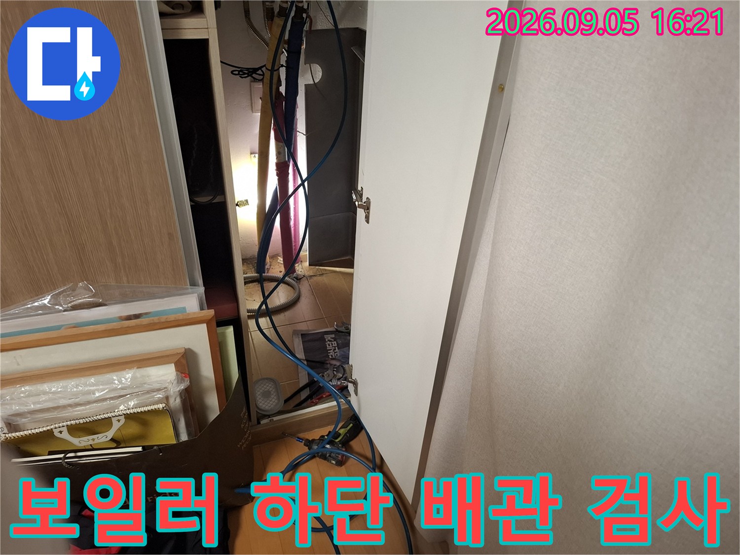보일러 아래쪽의 여러 배관들을 면밀히 관찰하고 있습니다.