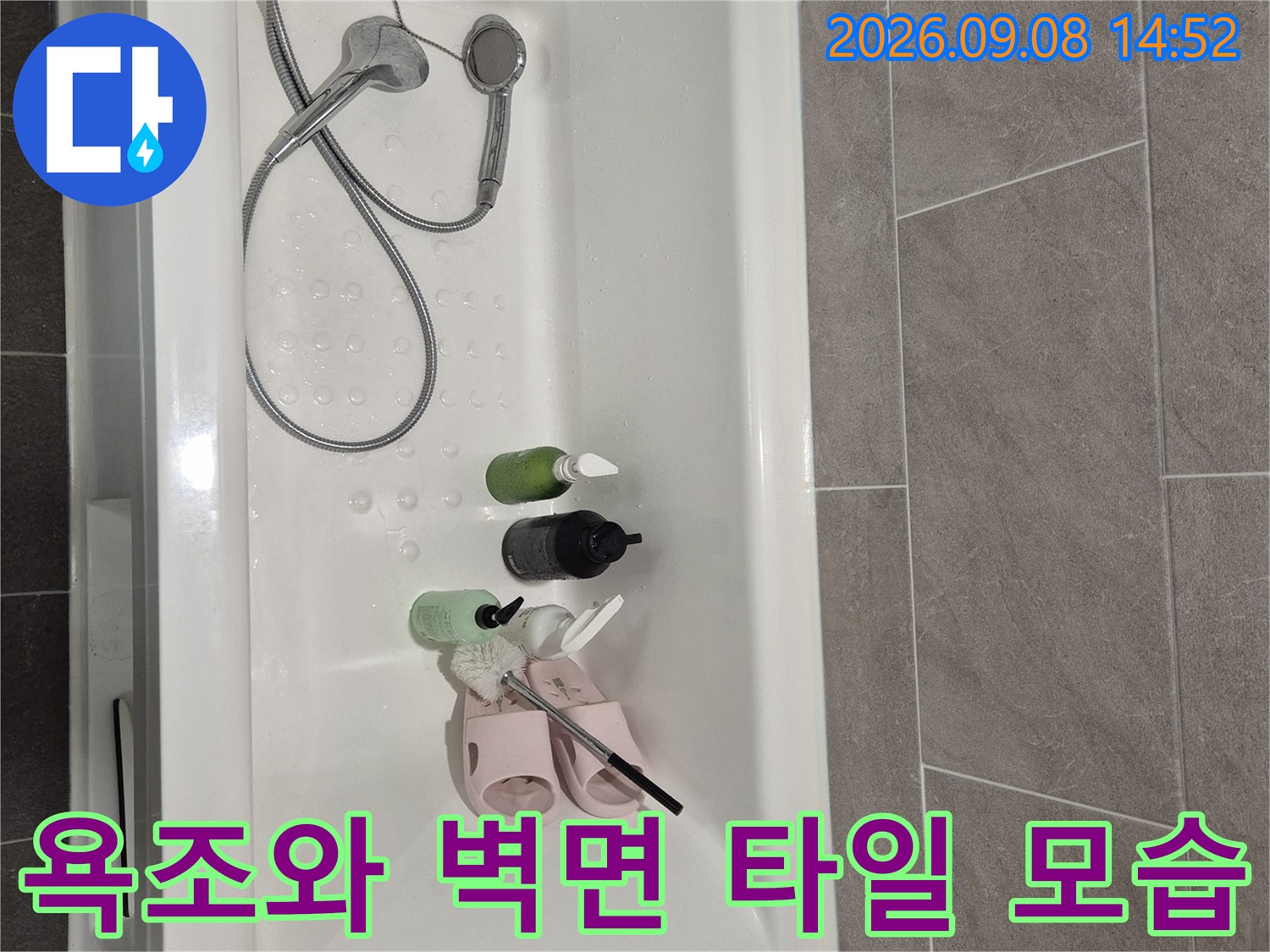 회색 타일 벽면과 흰색 욕조가 어우러진 욕실 내부입니다.