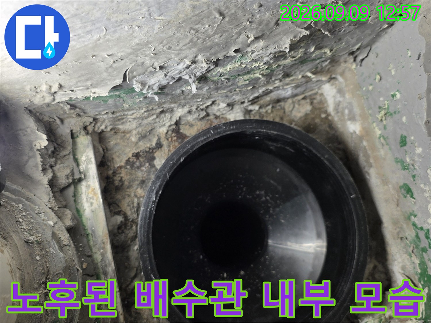 검게 보이는 배수관 입구와 주변의 거친 마감 상태를 보여줍니다.