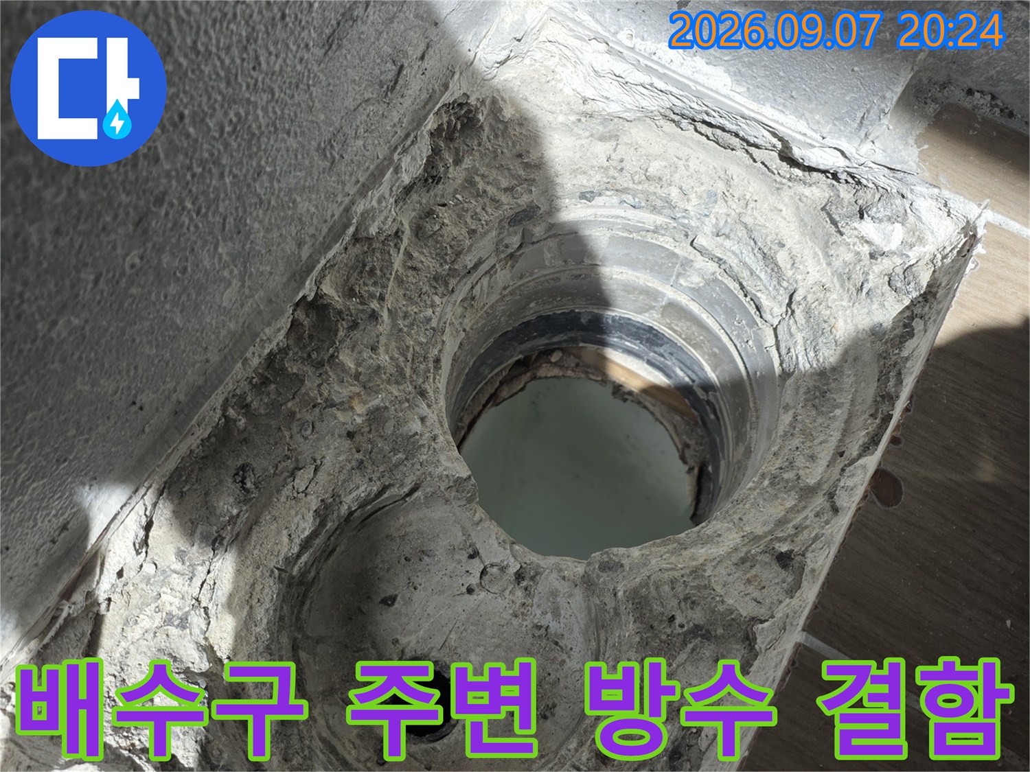 배수구 배관 주위의 파손된 방수재와 노출된 배관 연결 부위를 보여주는 사진입니다.