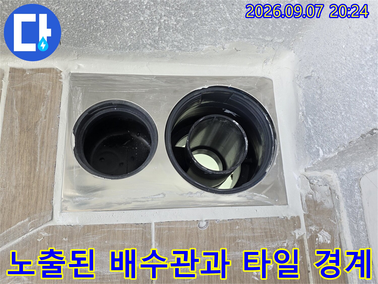 타일 마감면과 노출된 배수관 사이의 틈새를 근접 촬영한 사진입니다.