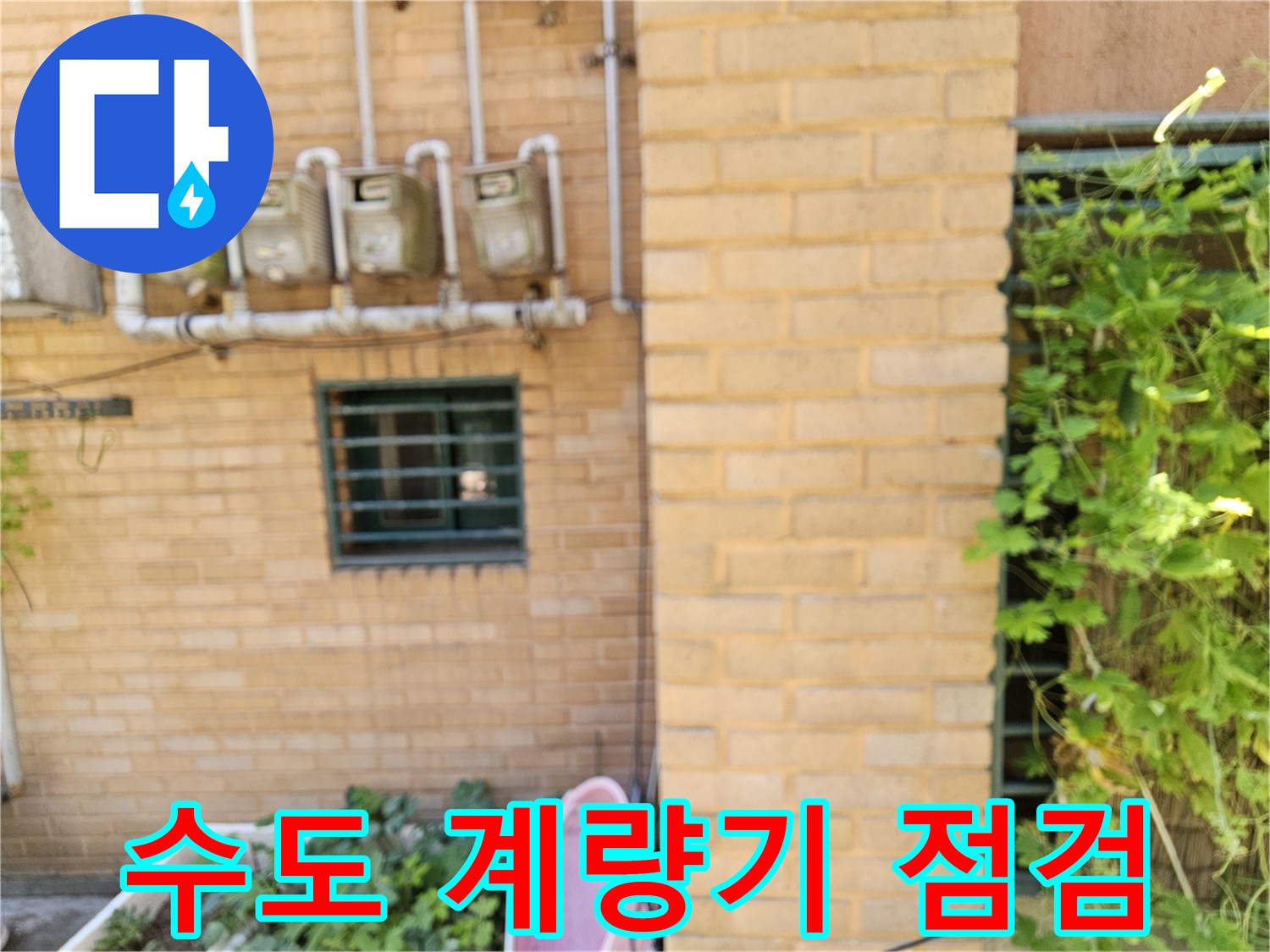 외벽 벽돌 구조물에 설치된 수도 계량기와 급수관의 모습