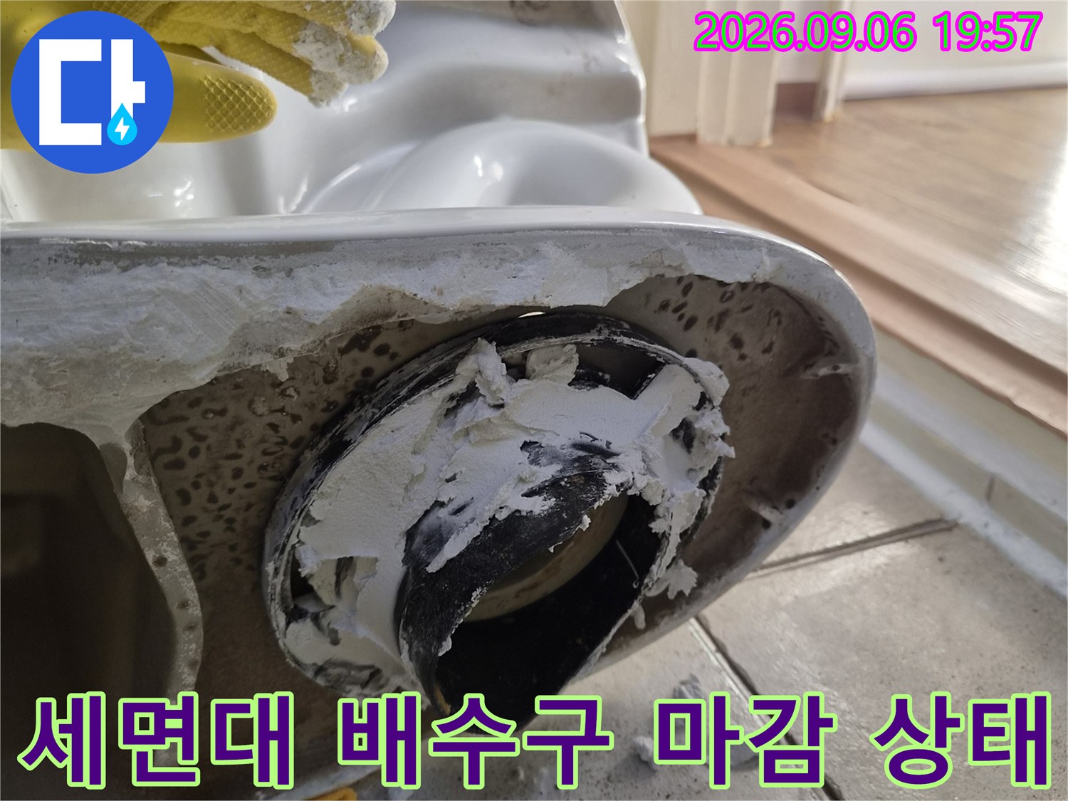 세면대 하부 배수구 주변의 노후된 마감재와 오염 상태를 보여주는 사진입니다.