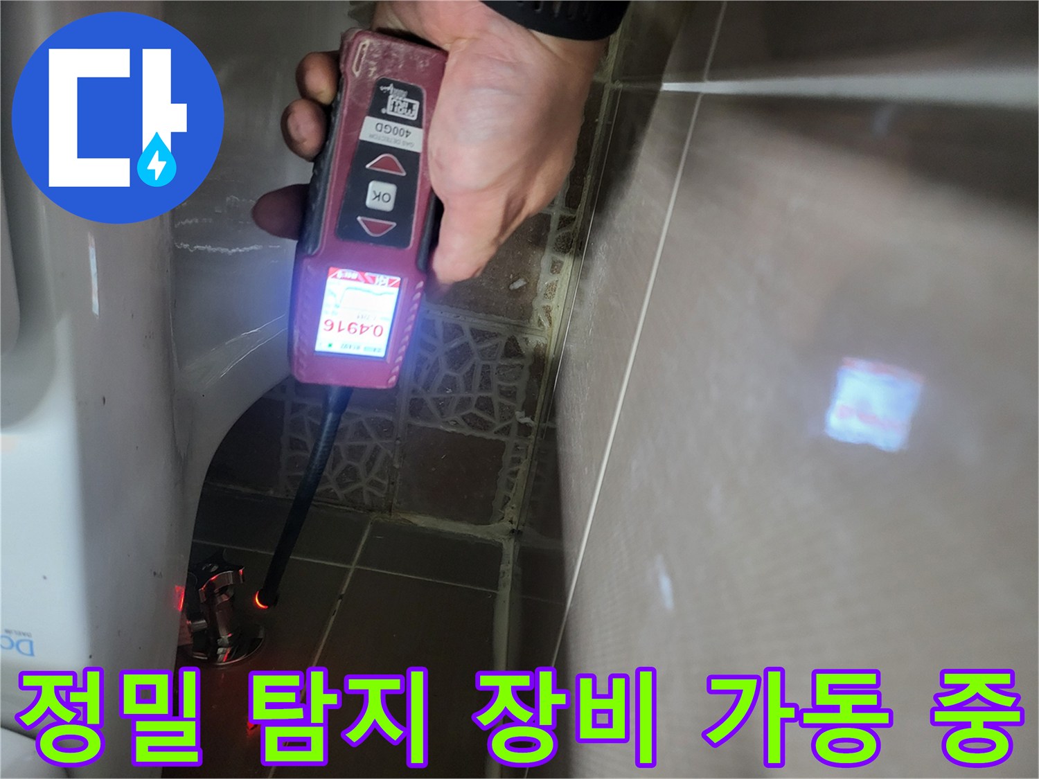 변기 뒤쪽 벽면을-가스식 탐지기로 꼼꼼하게 훑으며 누출 지점을 찾는 장면입니다.