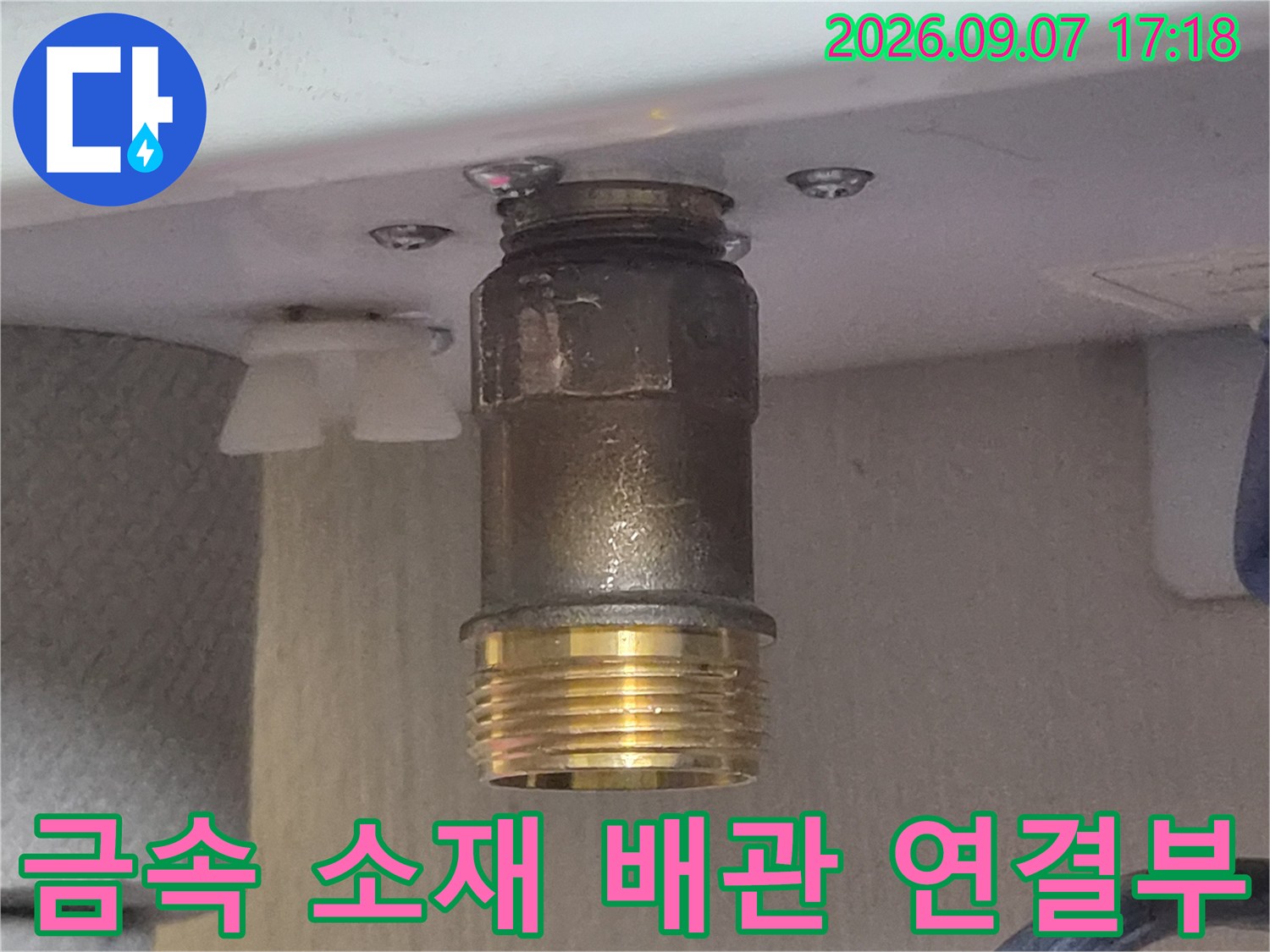 황동색 나사산과 금속 어댑터가 결합된 배관 부위 촬영