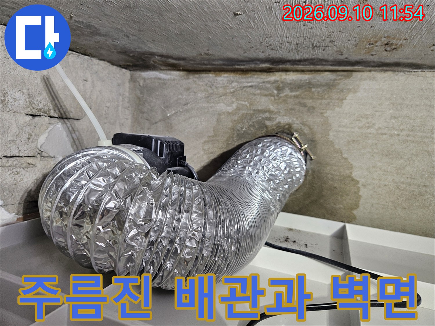천장 콘크리트 구조와 연결된 은색 주름 배관입니다.