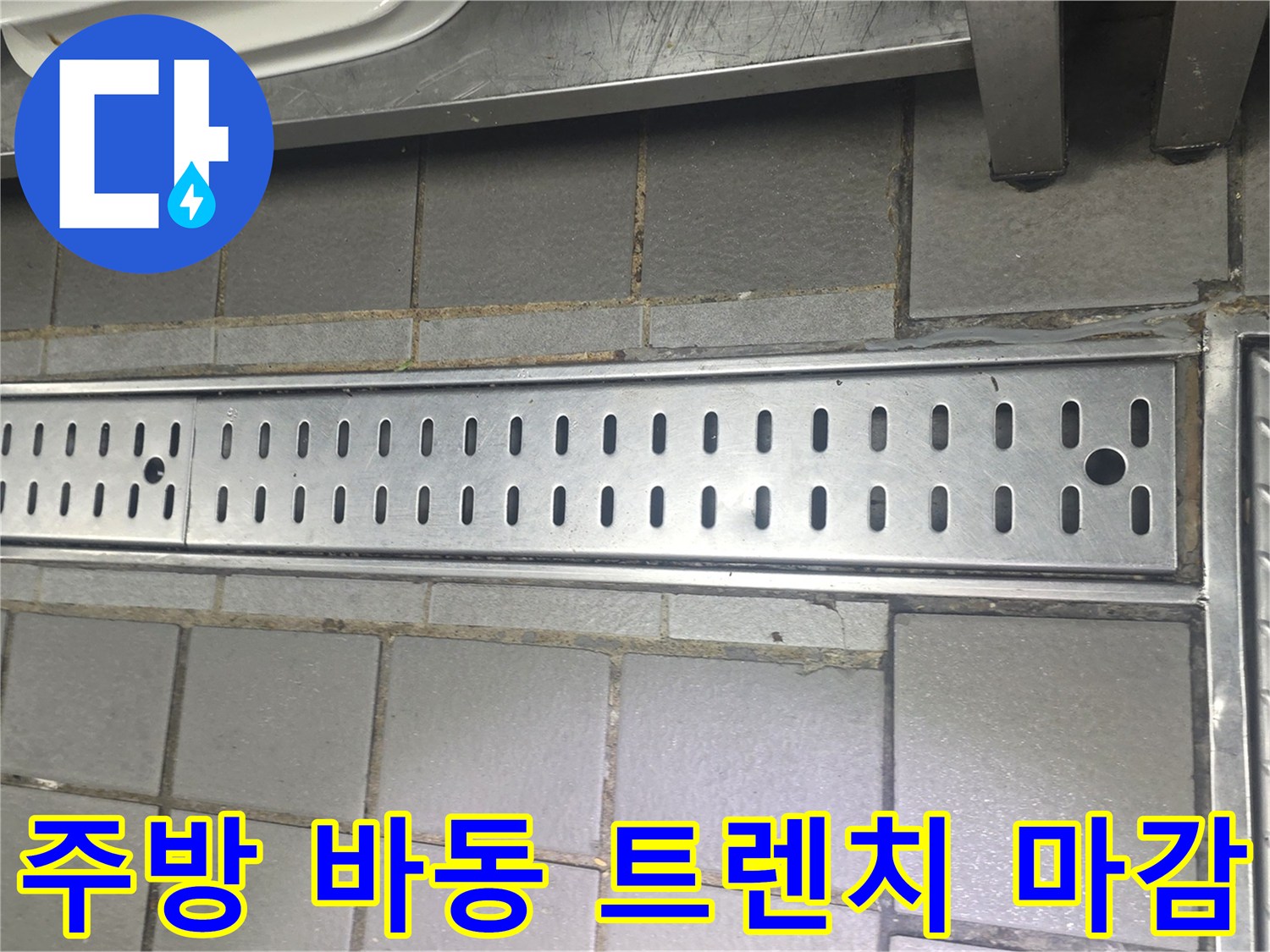 스테인리스 배수 트렌치와 회색 타일이 만나는 지점의 상세 사진