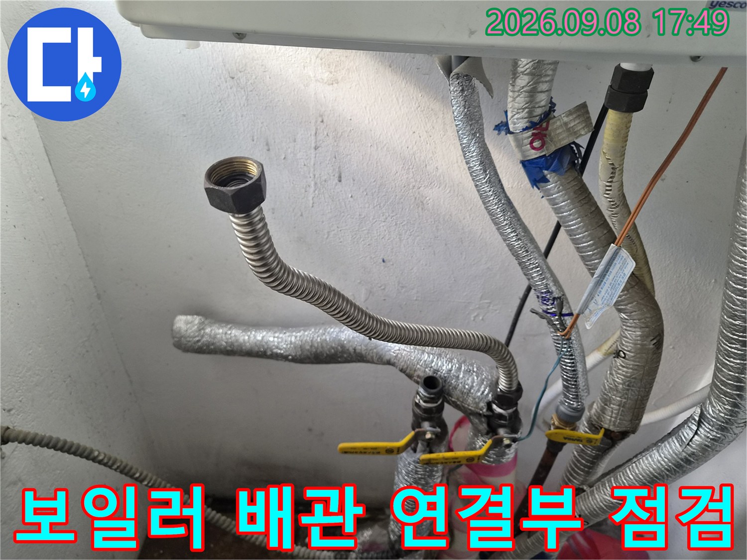 보일러 하단에 위치한 은색 보온재로 감싸진 배관과 노란색 밸브의 모습입니다.