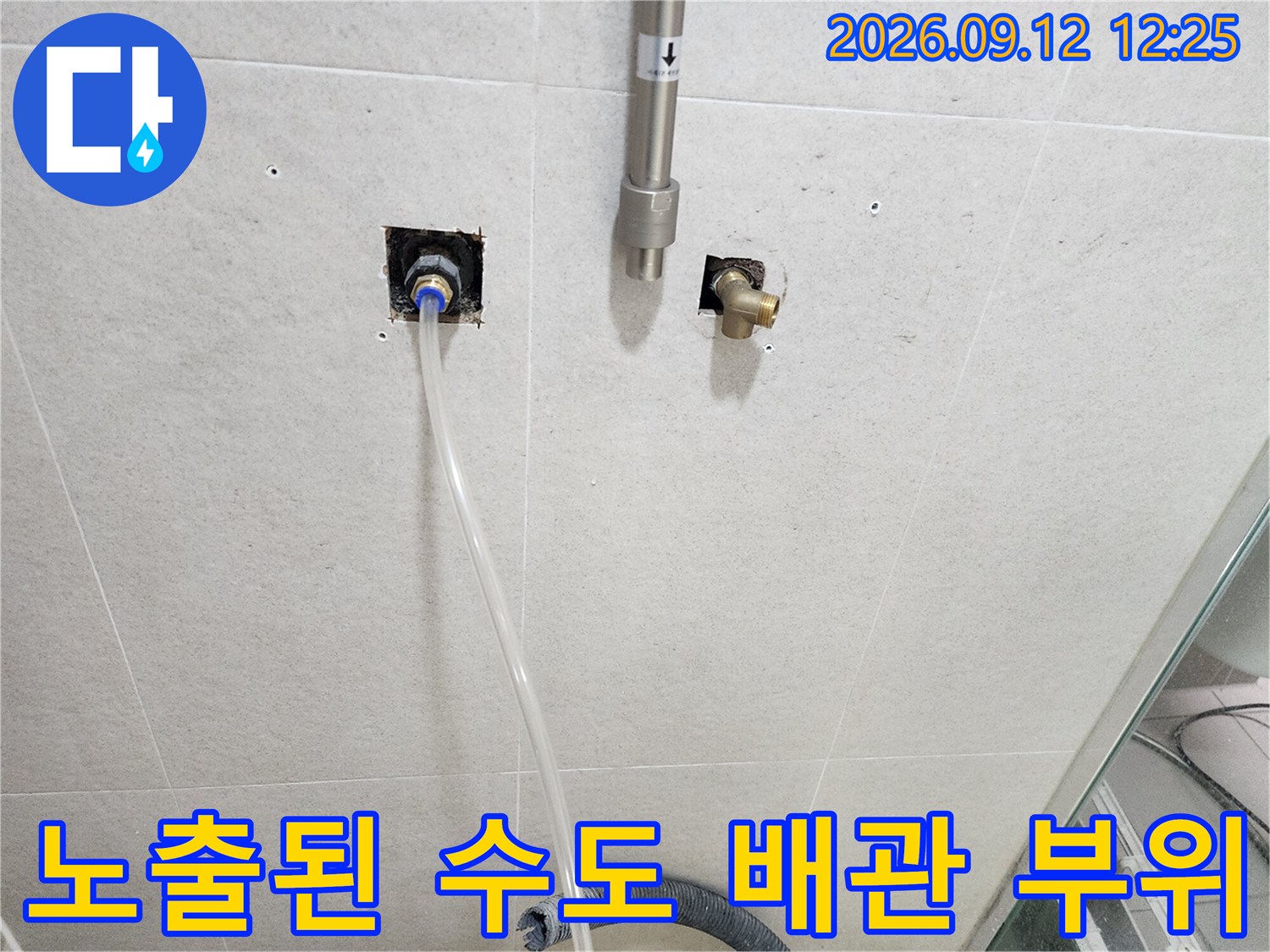 수도 연결부와 금속 밸브가 벽면에서 노출되어 있는 현장 사진입니다.
