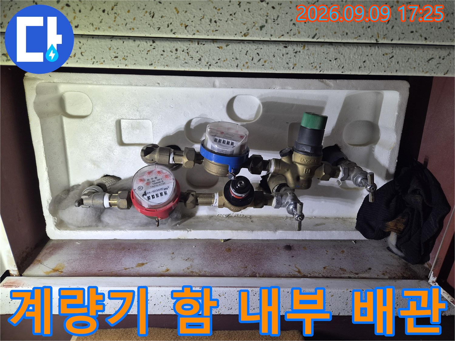 수도 계량기와 밸브가 복잡하게 연결된 계량기함 내부의 모습입니다.
