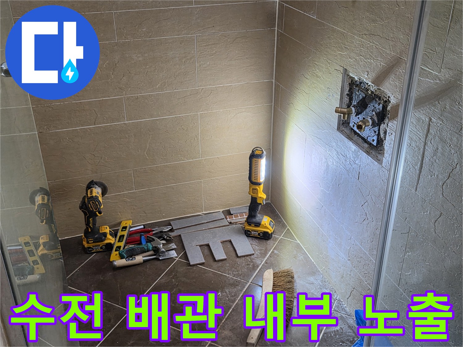 타일이 제거된 벽면에 드러난 샤워 수전용 배관 및 작업 장비