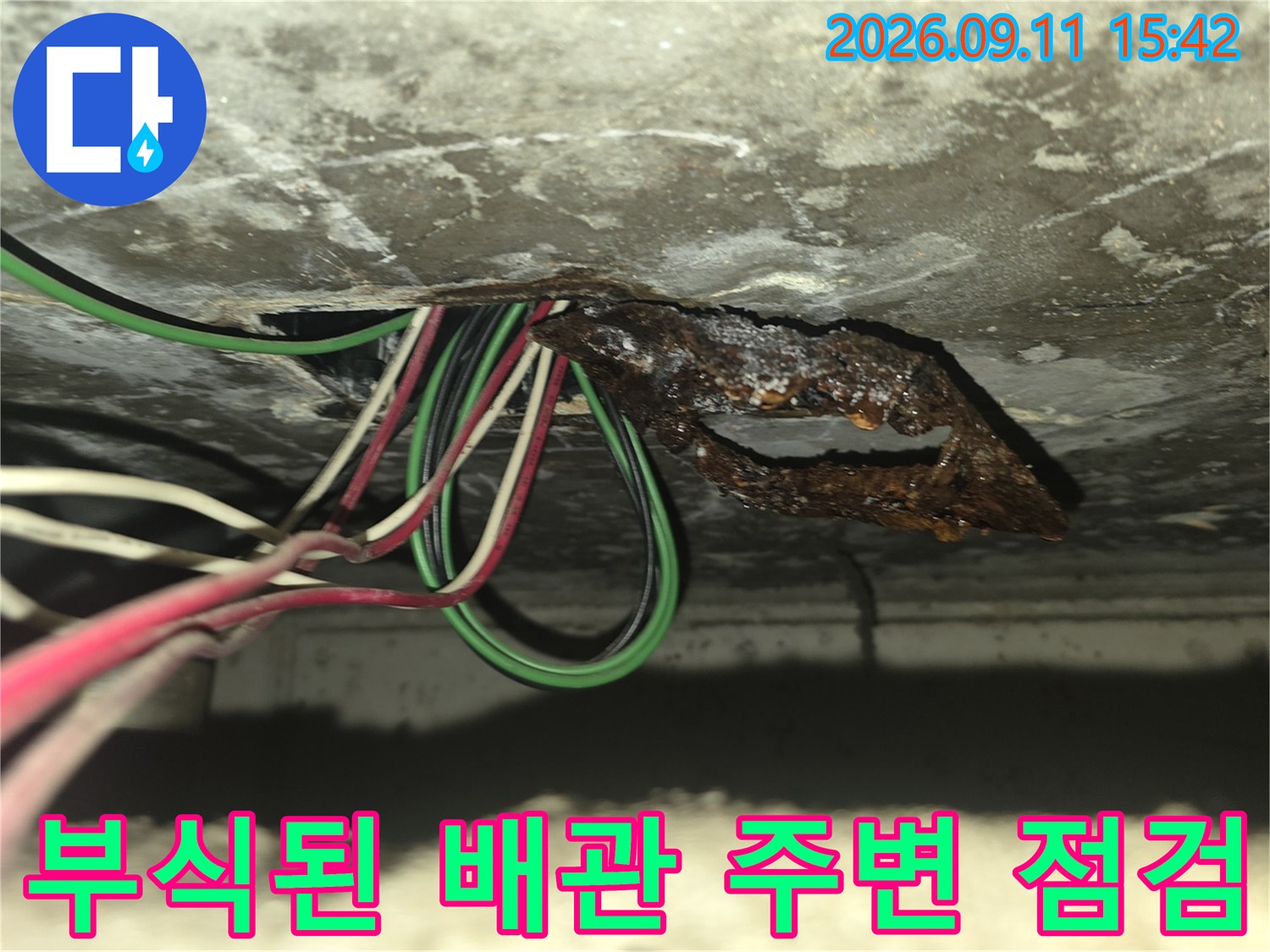 슬라브 천장에 노출된 전선과 부식되어 녹슨 금속판의 근접 촬영 이미지입니다.
