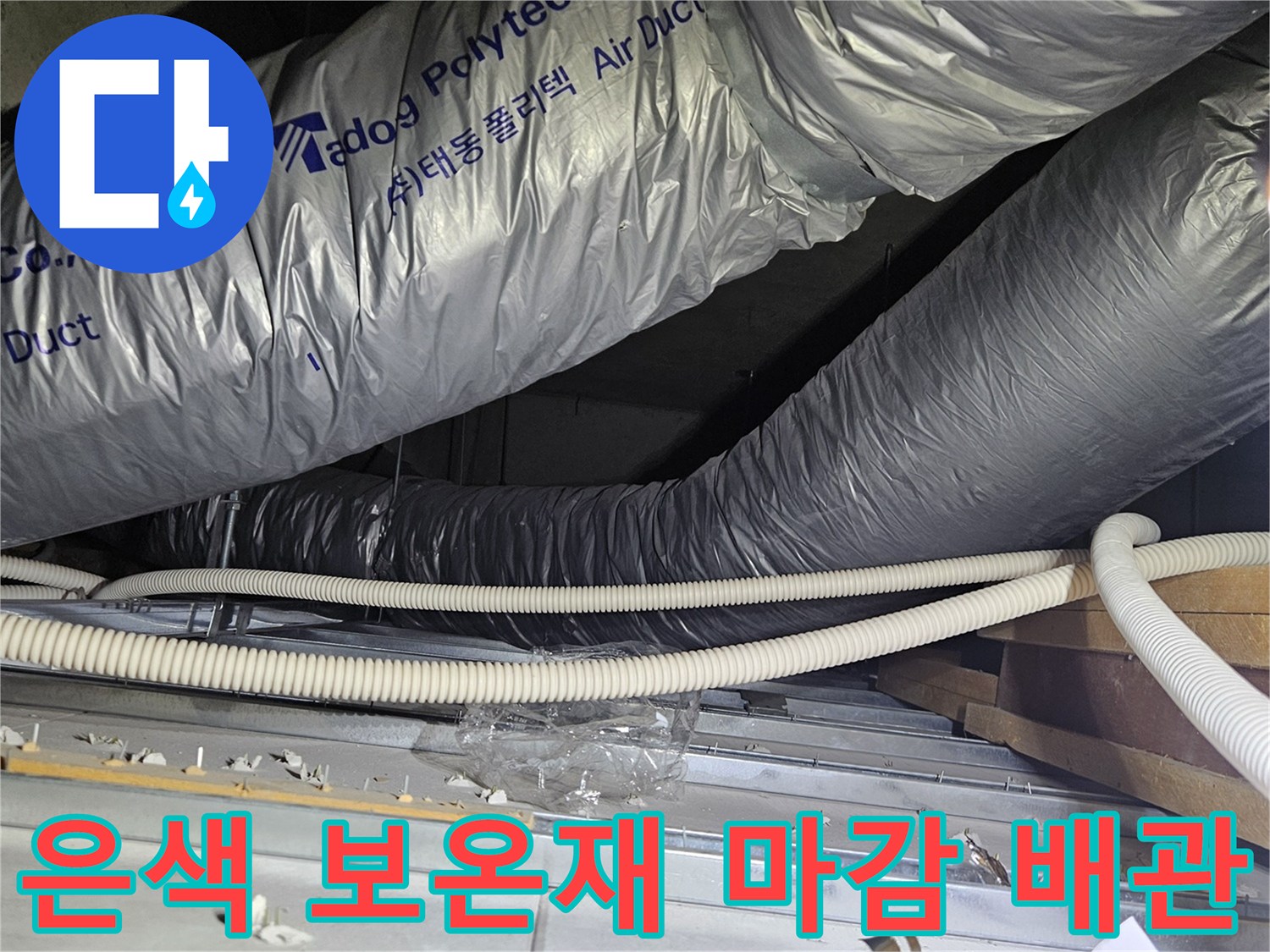 보온재로 감싸진 굵은 배관과 흰색의 얇은 전선 보호관이 나란히 지나가는 장면