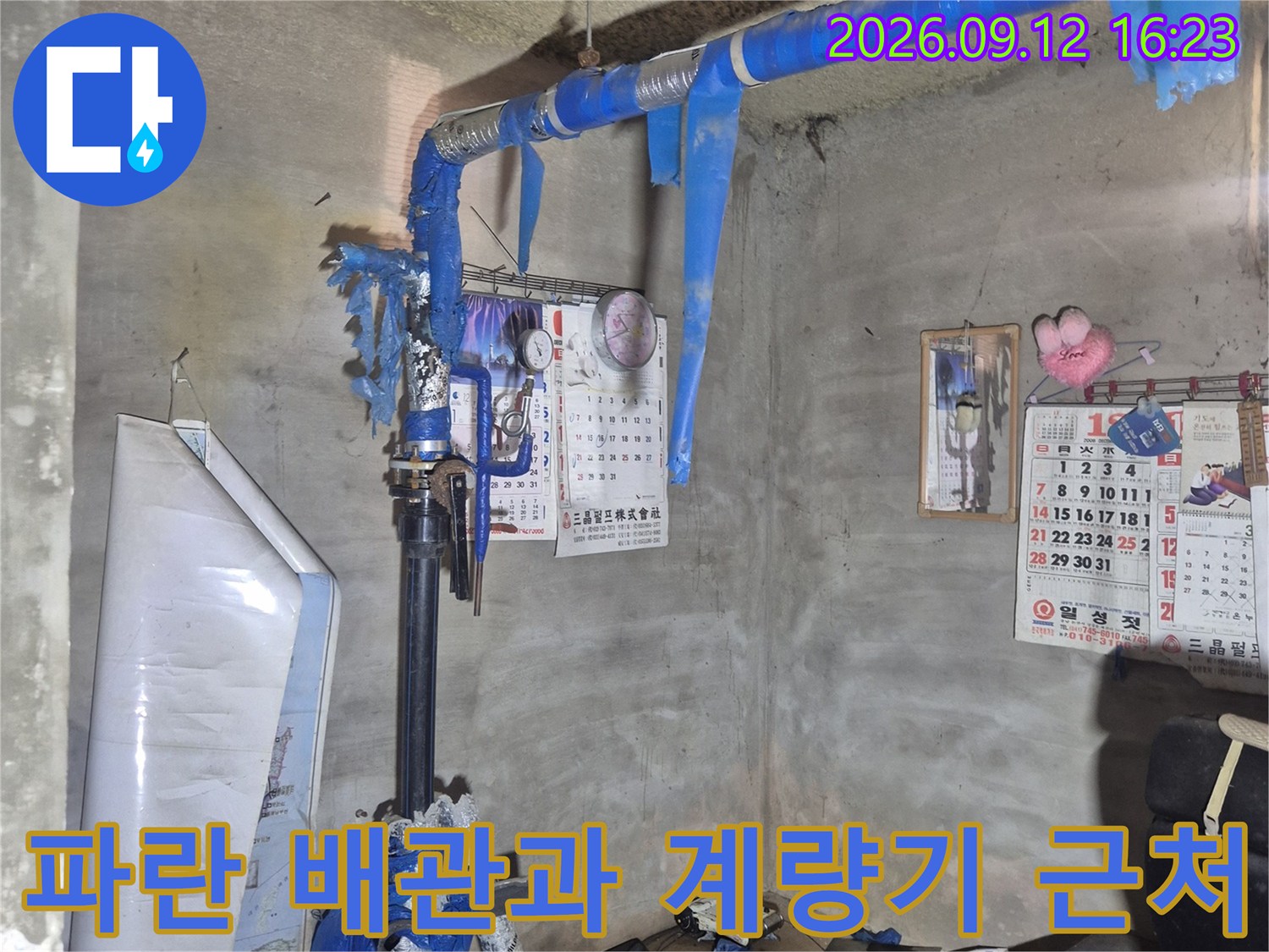 물기가 보이는 지하 공간의 파란색 보온재 배관과 계량기 시설