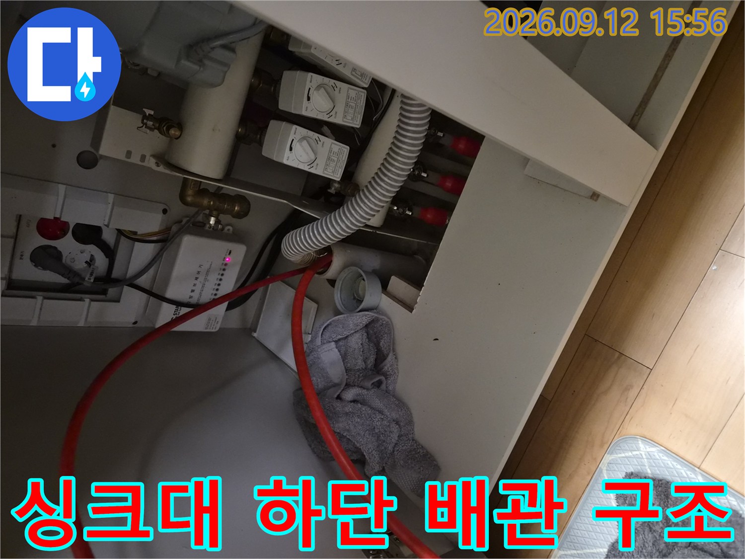 싱크대 아래쪽의 급수 밸브와 배수 호스 연결 부위 상세 사진