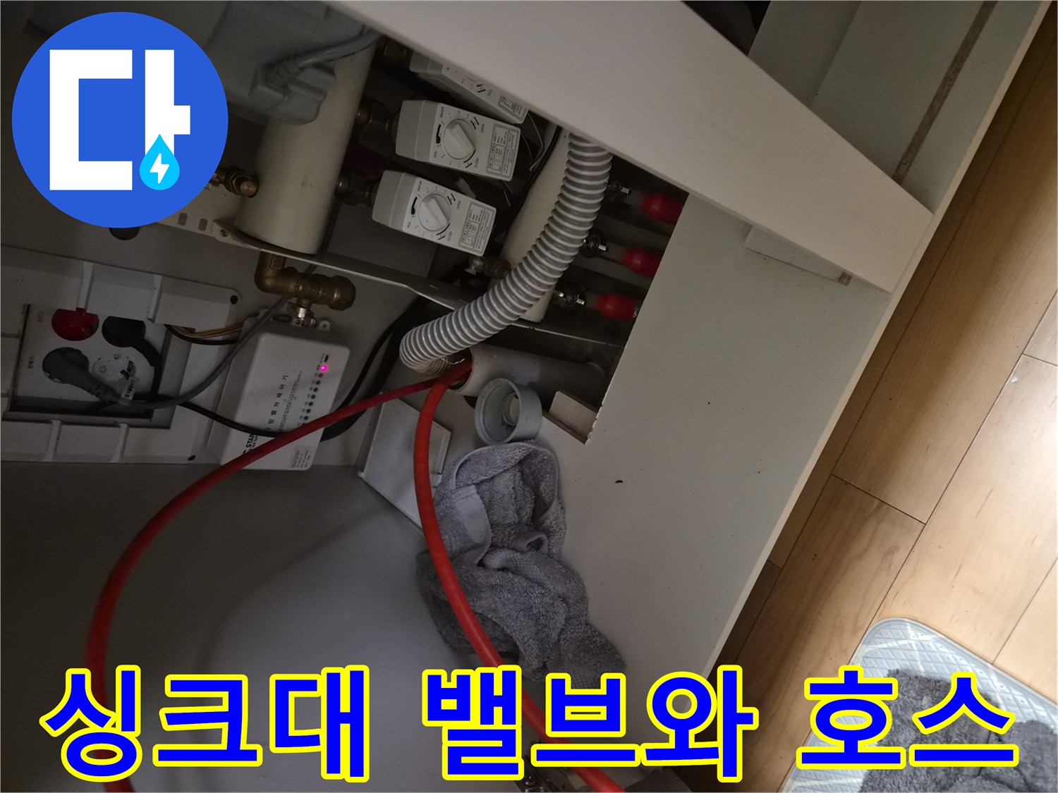주방 하부장 내부의 급수 밸브와 배수 연결 부위