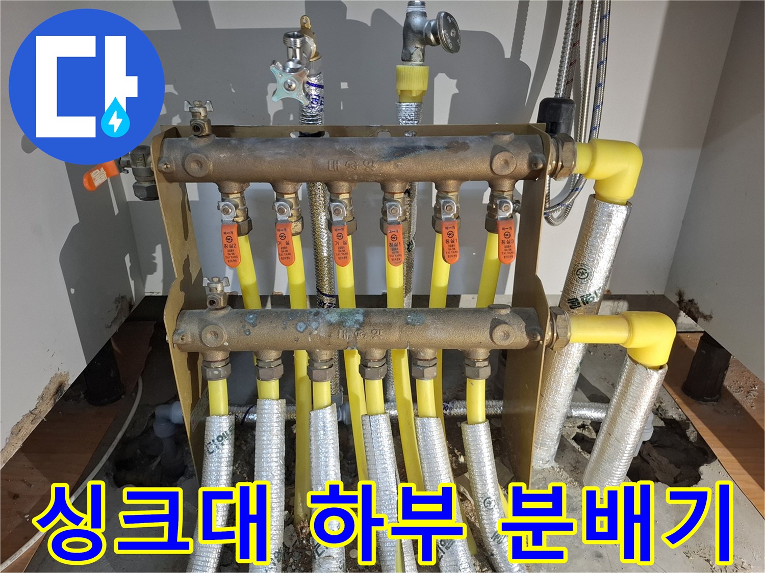 싱크대 아래 설치된 금속 재질의 난방 분배기와 배관 구조