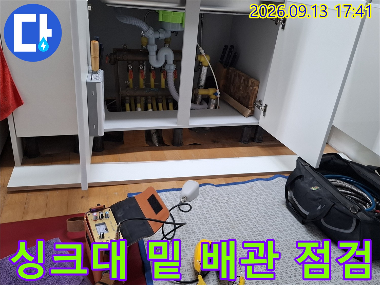 싱크대 하단부의 분배기와 노란색 배관이 드러난 누수 작업 현장