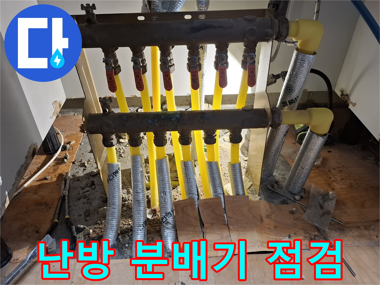 싱크대 하부장 아래 노출된 난방 분배기와 연결 배관 상태