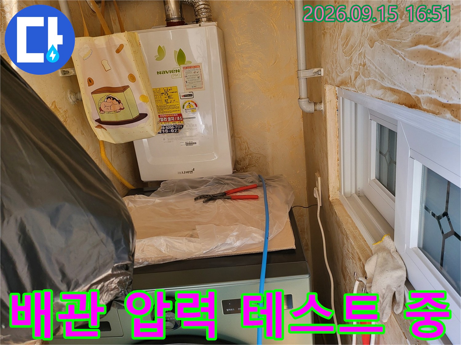 보일러 하단 배관에 연결된 노란색 호스와 정밀 측정 장비 모습입니다.