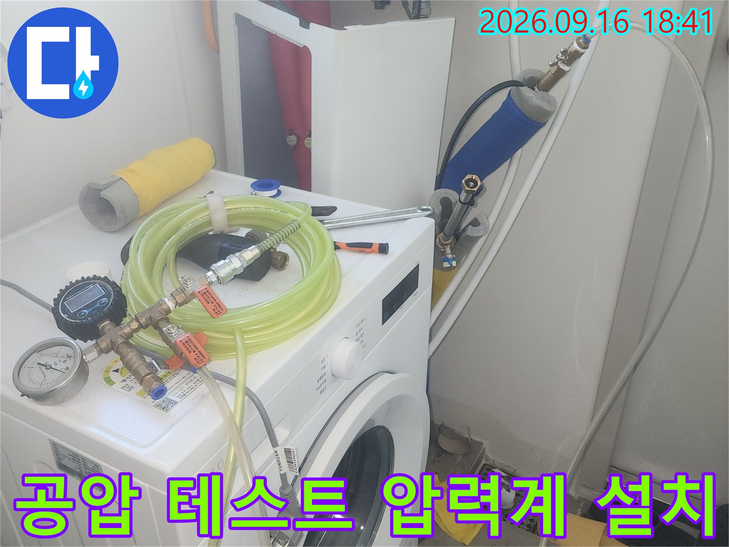 세탁기 옆 수도 밸브에 연결된 누수 탐지용 호스와 게이지 장치