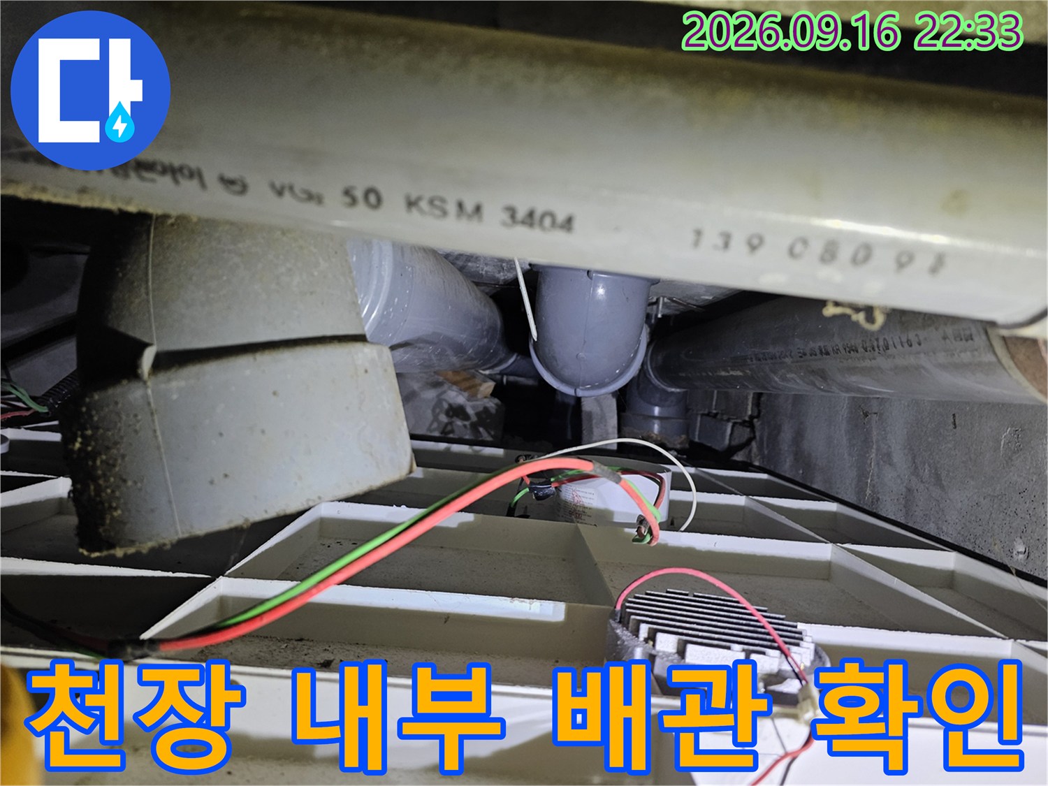 점검구 내부에 노출된 하수 배관과 전기 배선 구조